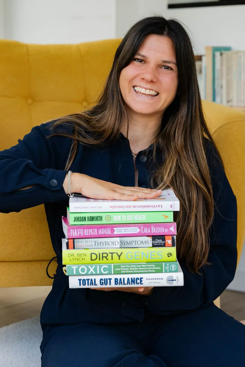Mélanie Padovani, souriante, tenant une pile de livres sur la santé intestinale